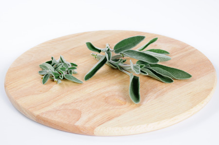 Pile of sage leaves and twigs on round wooden cutting board