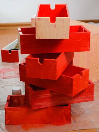 Six stacked freshly painted bright red wooden boxes standing on floorの写真素材
