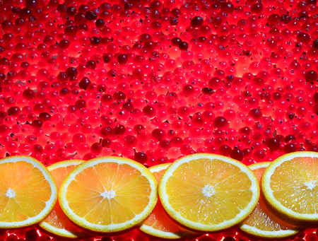 seven orange slices lie on ripe red cranberries that glow like the coals of a campfireの写真素材
