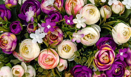Close-up image of a bouquet of artificial roses and carnations in red, violet, yellow and white and...