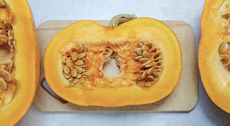 Pieces fragments of a small orange pumpkin lie on a table and a cutting Board close-up.の写真素材