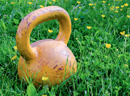 Round old yellow weight lies on a field of flowers buttercups closeup.の写真素材
