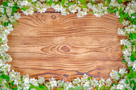 Jasmine branches with white flowers with green leaves lie on a wooden table made of old vintage...