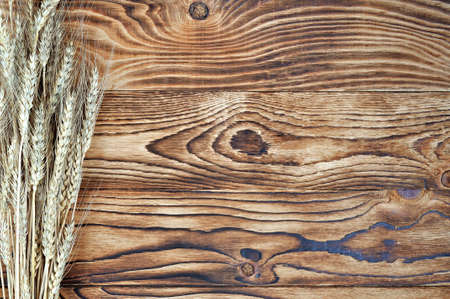 Ripe pile of wheat ears with seeds ready grain on the background of an old wooden textured table of a rural house.の写真素材