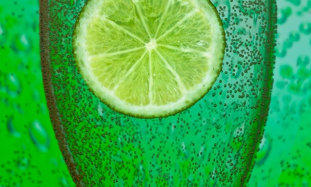 slice of lime with bubbles and glassの写真素材