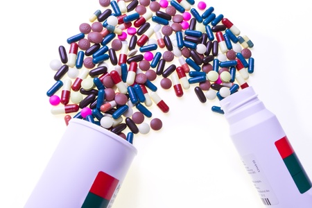 colorful pills spilling out of container, isolatedの写真素材