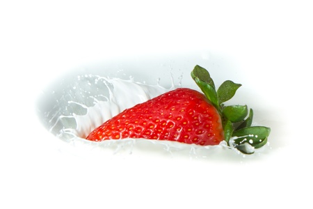 delicious fresh strawberry falling into splashing milkの写真素材