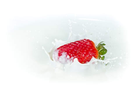 delicious fresh strawberry falling into splashing milkの写真素材