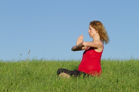 beautiful pregnant woman practicing yoga on a meadowの写真素材