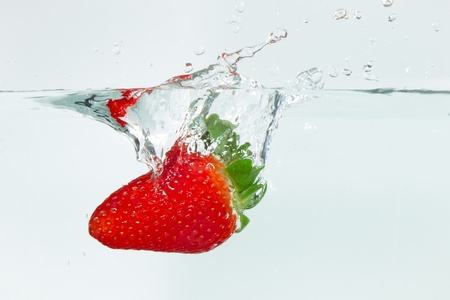 fresh strawberry dropped into water with splash on white backgroundsの写真素材
