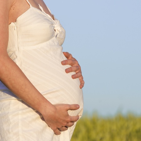 pregnant woman in white dress relaxing outdoorsの写真素材