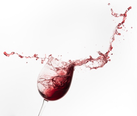 red wine splashing out of a glass, isolated on whiteの写真素材