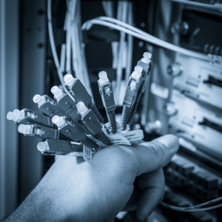 hand  of administrator holding bunch of optic fiber cables with connectors