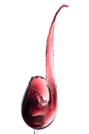 red wine splashing out of a glass, isolated on whiteの写真素材