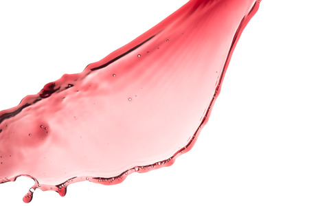 red wine splashing out of a glass, isolated on whiteの写真素材
