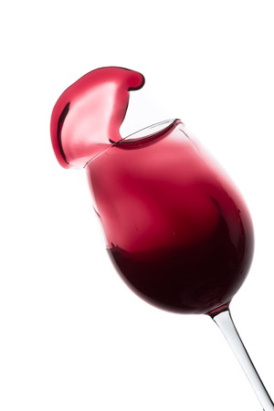 red wine splashing out of a glass, isolated on whiteの写真素材
