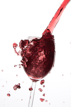 pouring red wine in goblet, isolated on whiteの写真素材