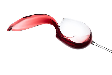 red wine splashing out of a glass, isolated on whiteの写真素材