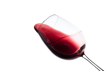 red wine splashing out of a glass, isolated on whiteの写真素材