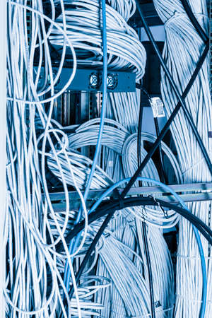 server room rack with tangled network cables creating messy untidy network systemの写真素材