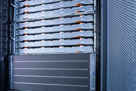 server rack with uncovered data storage arrays filled with hard drives - internet cloud provider...