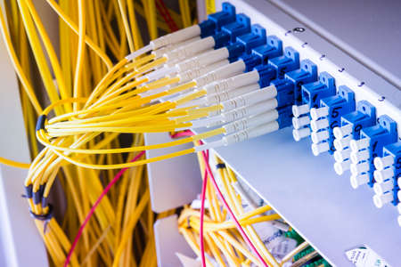 fiber optic cables plugged in network switch panel inside data center