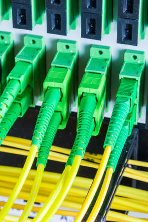 fiber optic cables plugged in network switch panel inside data center