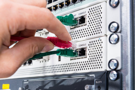 Hand of computer technician connecting patch cable into data switchの写真素材