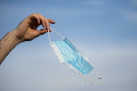 medical mask in hands against the sky. Pandemic endingの写真素材