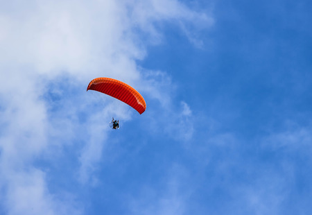 Paragliding  a sport is resembling a parachute is attached to a person's body by a harness in order to allow them to glide through the air after jumping from or being lifted to a height.の写真素材