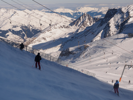 Several skiers stopped on a slope by strong wind on Hintertux glacier in Austrian Alpsの写真素材