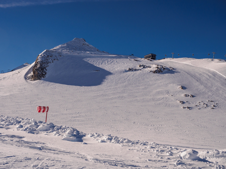 White snow and a weather sock indicating strong wind in Austrian Alpsの写真素材
