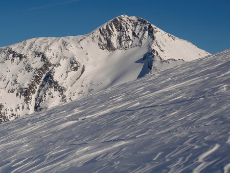 Snow covered rocky summit of a mountain against clear blue sky in Austrian Alpsの写真素材
