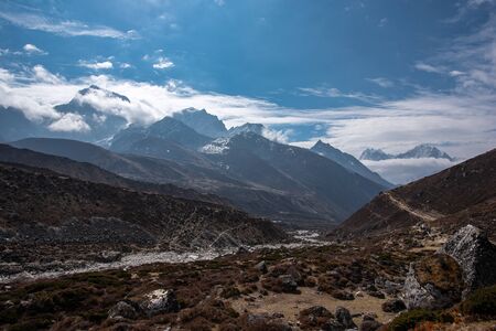 Landscape high in Nepal Himalayas with group of tourists on narrow path and moutain tops in the...