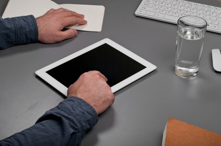 Man working with a tablet computer. Man clicks on the screen tablet computer on a gray desktop. Top viewの写真素材