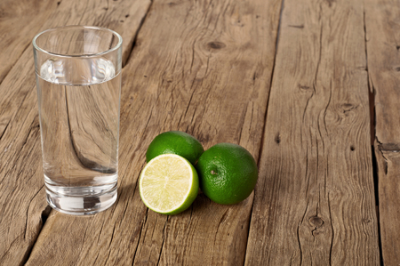 Glass of water with lime on a wooden background closeup.の写真素材