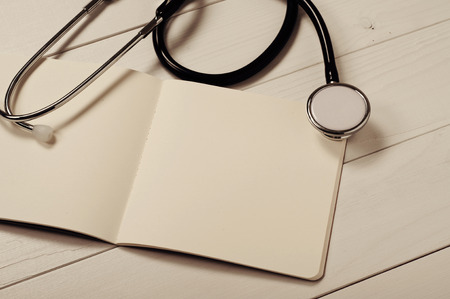 Closeup open notebook with blank pages with stethoscope on a white doctor\'s table.の写真素材