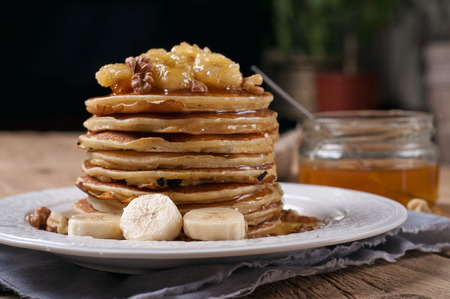 Pancakes with caramelized banana, nuts and honey on wooden table closeupの写真素材