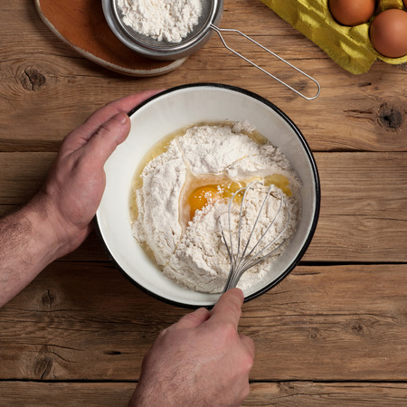 Products for the preparation of dough for bakery products. Male chef whisk egg closeup. Square frame