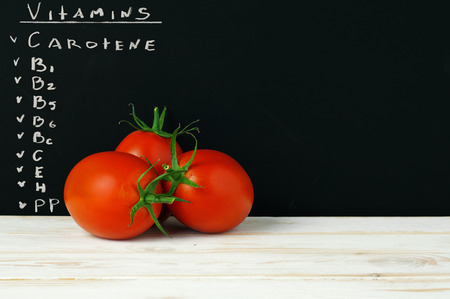 three tomatoes on a black background with a description of useful properties. Vitamins. Close upの写真素材