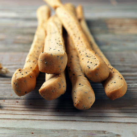 breadsticks with poppy seeds with ears of wheat on the wooden table