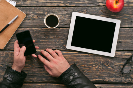 man working outside the office with the help of digital devices on a dark wooden table in a cafe, top viewの写真素材