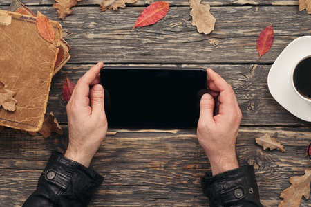 Men reading a using a tablet computer in cafe, top viewの写真素材