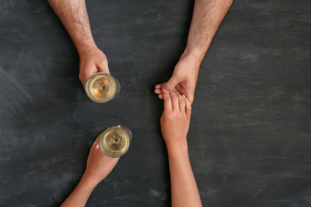 loving couple holding hands and drinking wine, top view