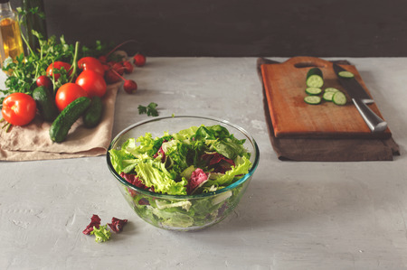 Full bowl of fresh green salad on a light table on a rustic kitchen.の写真素材