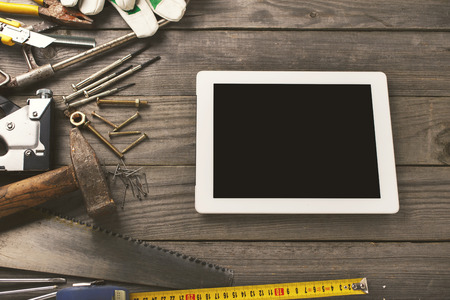 old tools on a wooden table with tablet with a blank screen in the workshop, top viewの写真素材