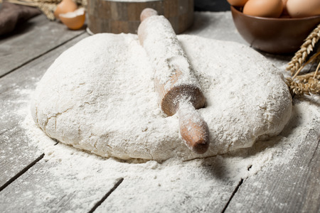 Rolling pin with flour close up on wooden table in bakery. Bakery backgroundの写真素材