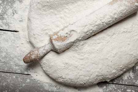 Rolling pin with flour close up on wooden table in bakery, top view. Bakery backgroundの写真素材