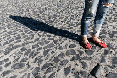 Female foot in torn jeans and red loafers close upの写真素材