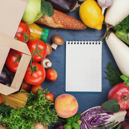 Full paper bag of food products and notebook with copy space on blue background, top viewの写真素材